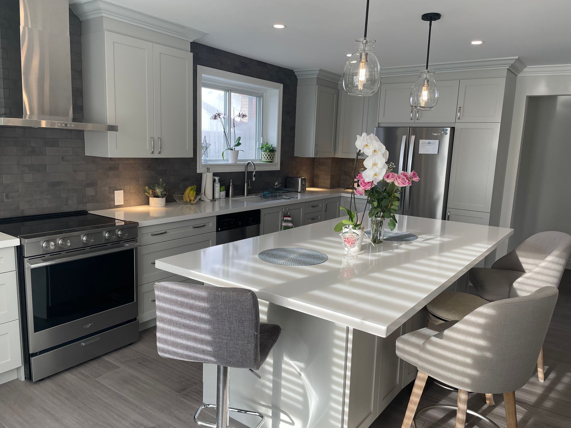 A kitchen with white cabinets , stainless steel appliances , and a large island.