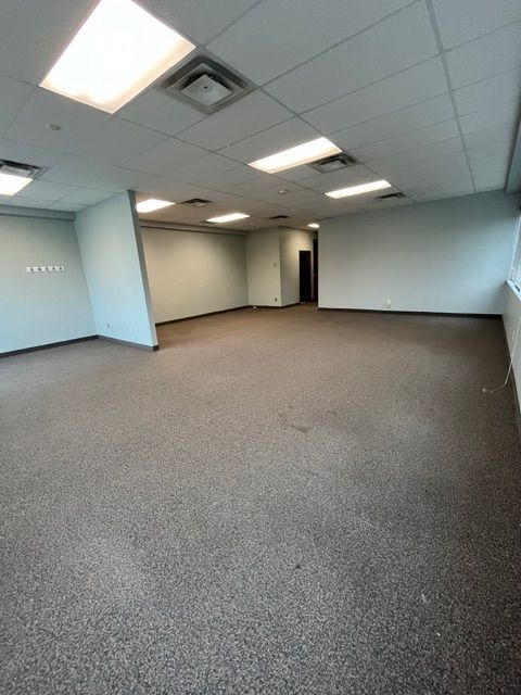 Empty office space with gray carpet, white ceiling, and light blue walls.