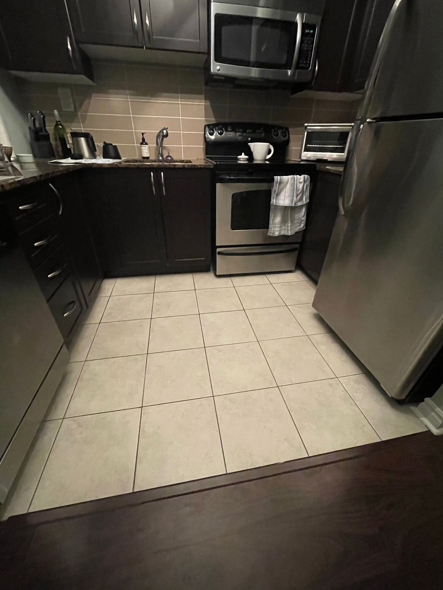 A kitchen with stainless steel appliances and a tiled floor