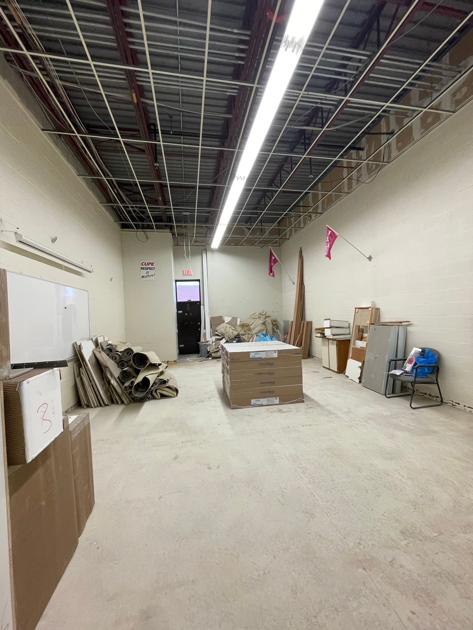 An unfinished room with exposed ceiling, concrete floor, and scattered materials, awaiting renovation.