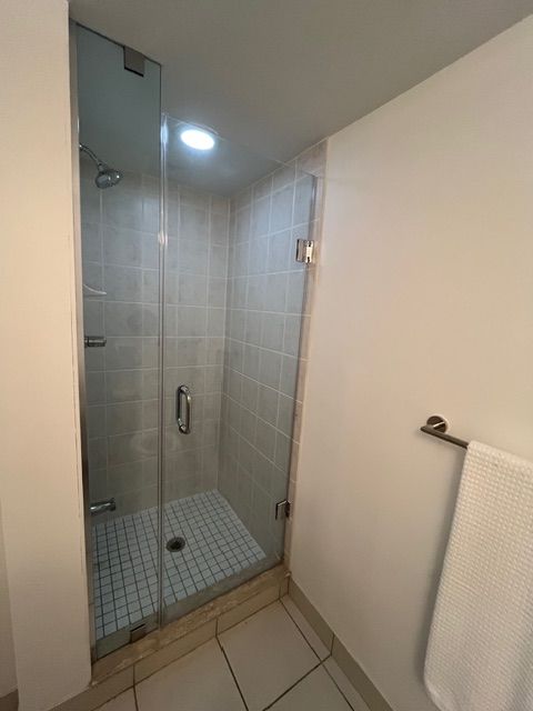 Glass shower stall with tile walls and floor. A towel rack is on the right wall.