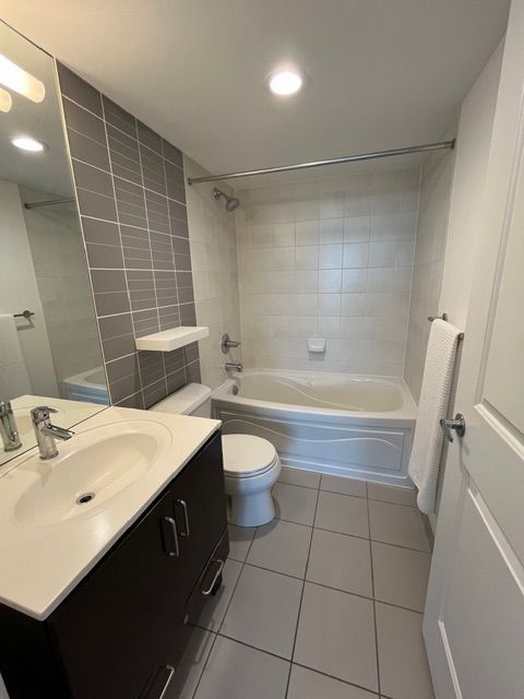 Bathroom with a bathtub, toilet, sink, and tiled walls and floor.