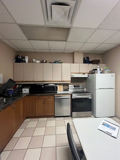 Kitchen with beige cabinets, stainless steel appliances, and tiled floor.