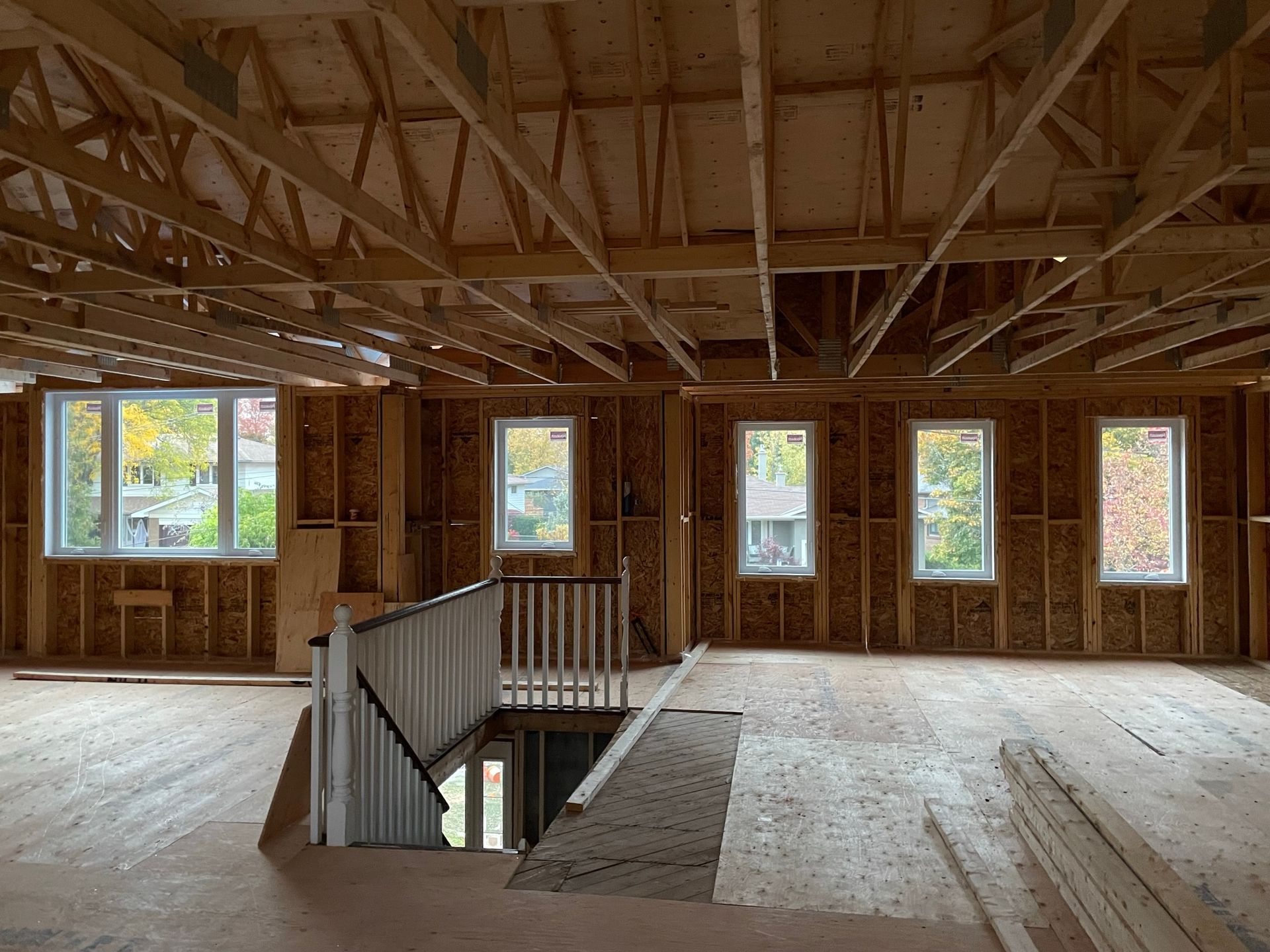 The inside of a house under construction with a staircase and lots of windows.