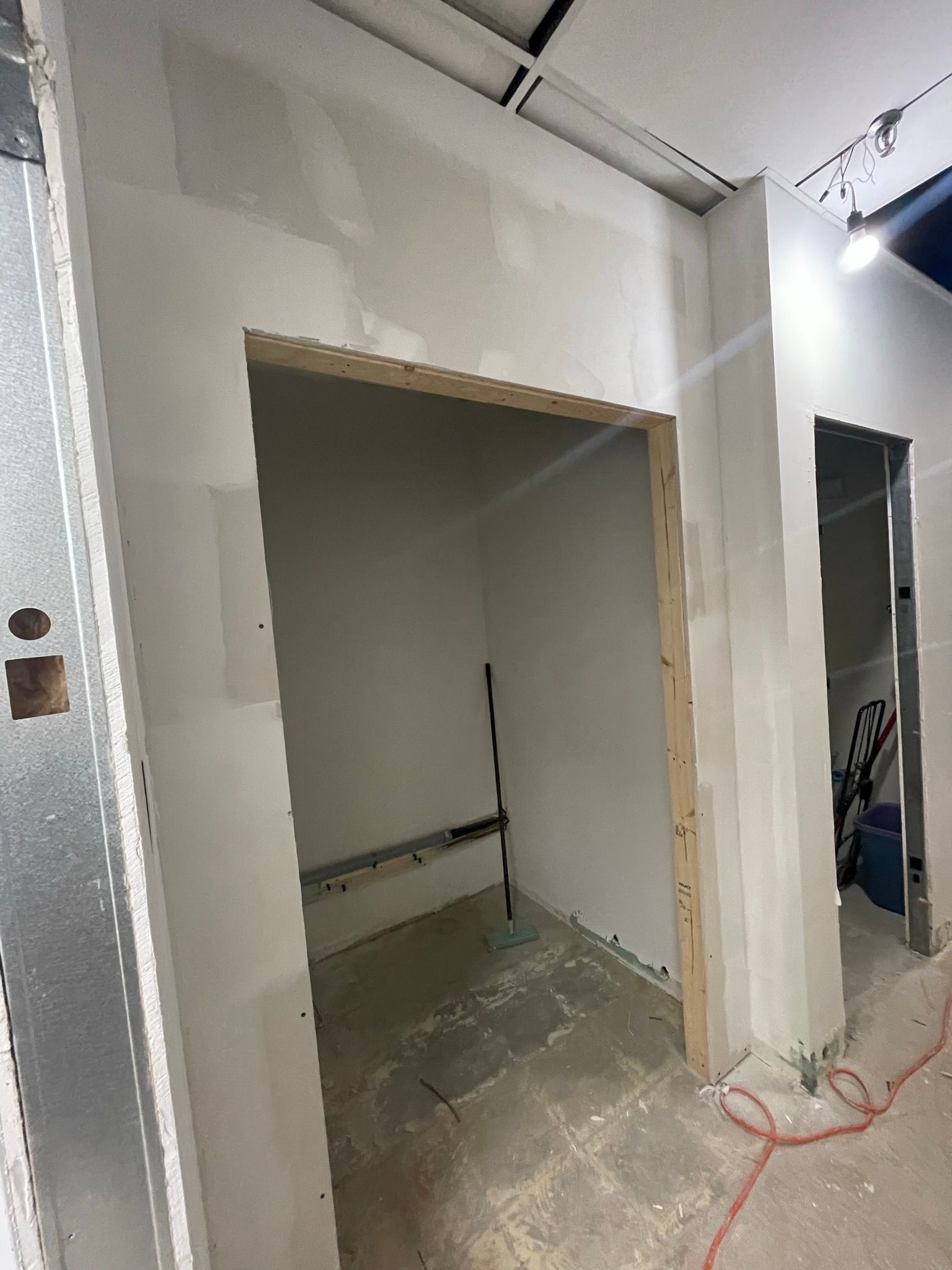 Interior room under construction, with open doorway and drywall.