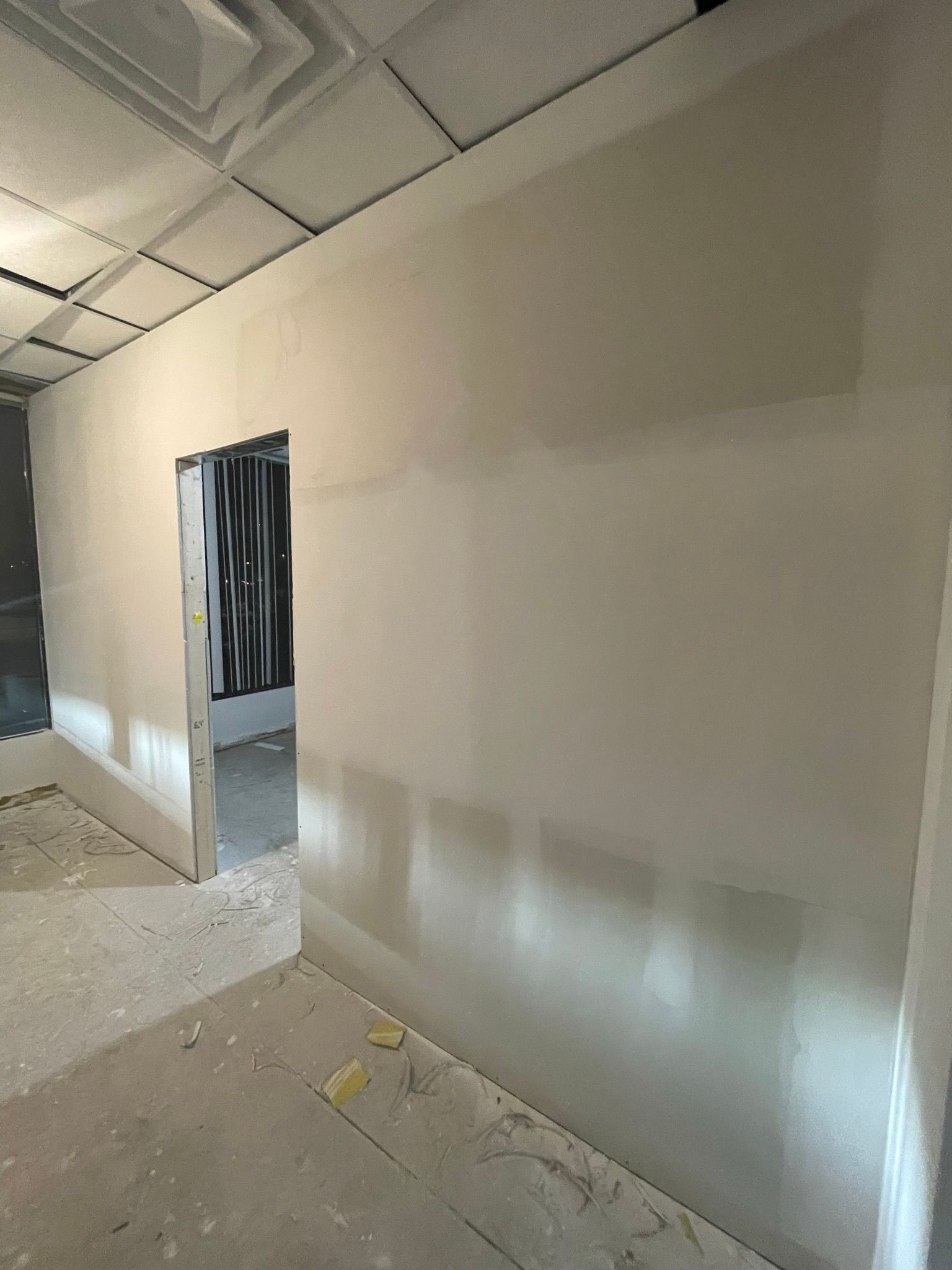 Interior room under construction with plastered walls, doorway, and unfinished ceiling.