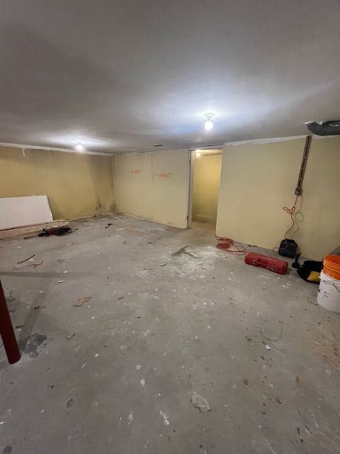 Basement with concrete floor, yellow walls, and tools scattered about. Unfinished construction.