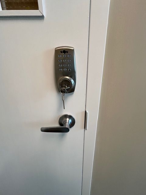 White door with a keypad lock, handle, and key.