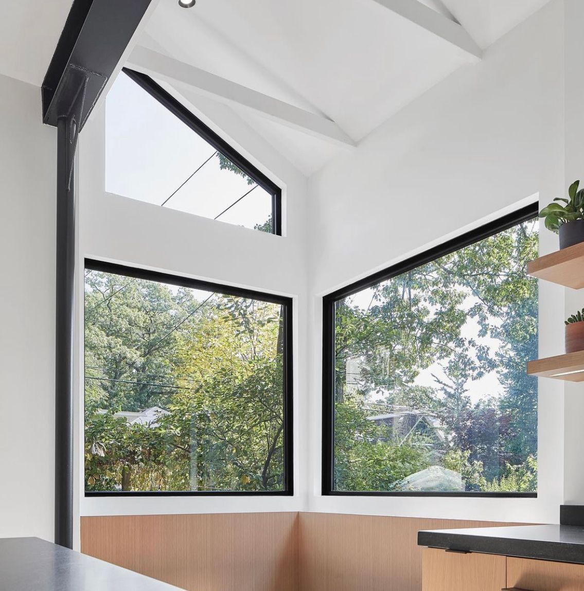 A kitchen with a lot of windows and trees in the background