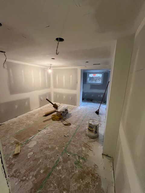 Interior room under construction, drywall installed, tools and debris on the floor, unfinished.