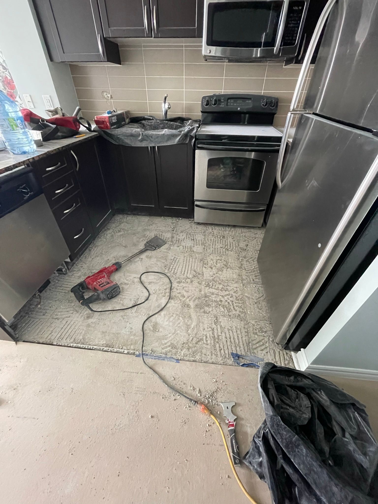 A kitchen with a stove , refrigerator , microwave and sink.