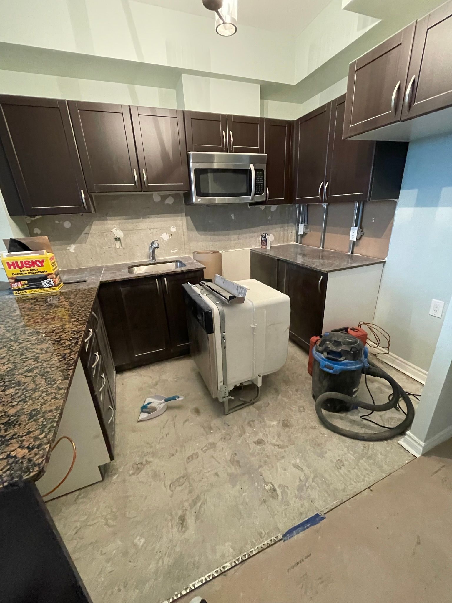 A kitchen with a vacuum cleaner sitting on the floor.
