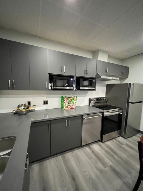 Modern kitchen with gray cabinets, stainless steel appliances, and gray countertops.