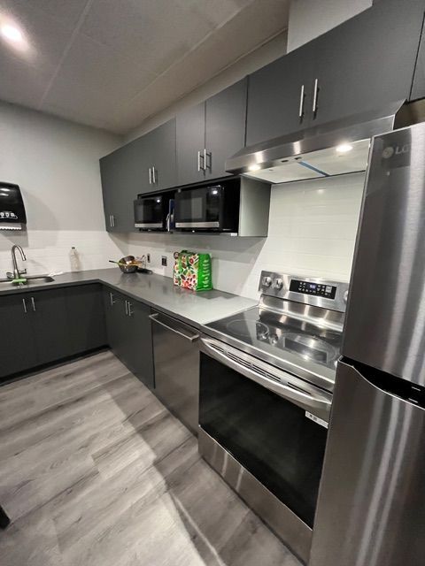 Modern gray kitchen with stainless steel appliances, countertops, and cabinets.