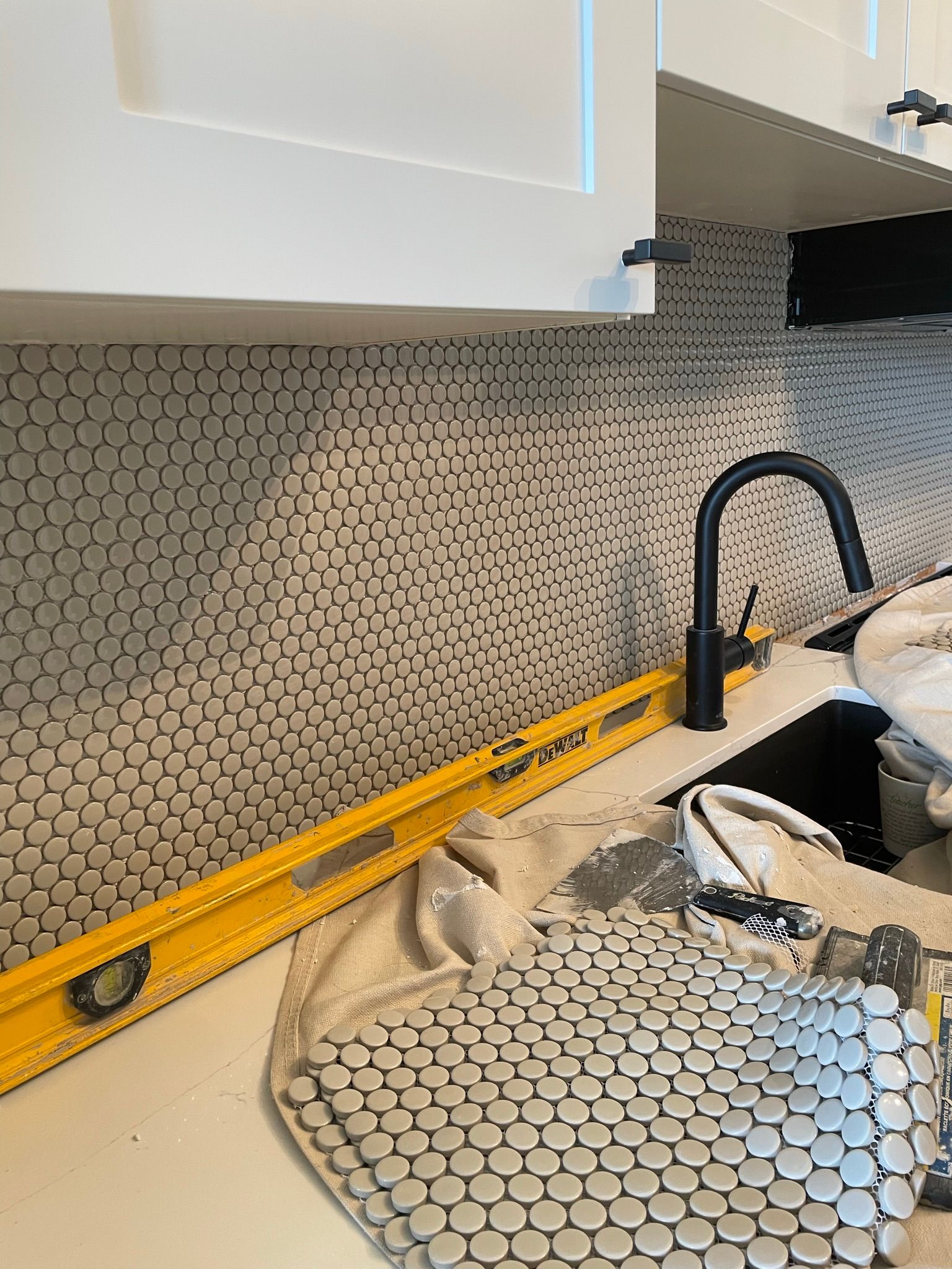 A yellow level is sitting on top of a kitchen counter next to a sink.