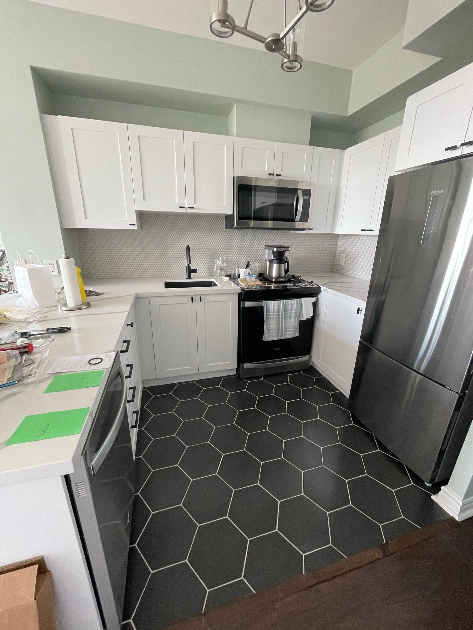 A kitchen with white cabinets , stainless steel appliances , a stove and a refrigerator.