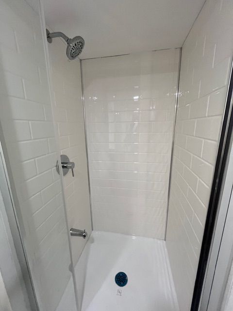 White shower stall with subway tile and glass door, water fixtures visible.