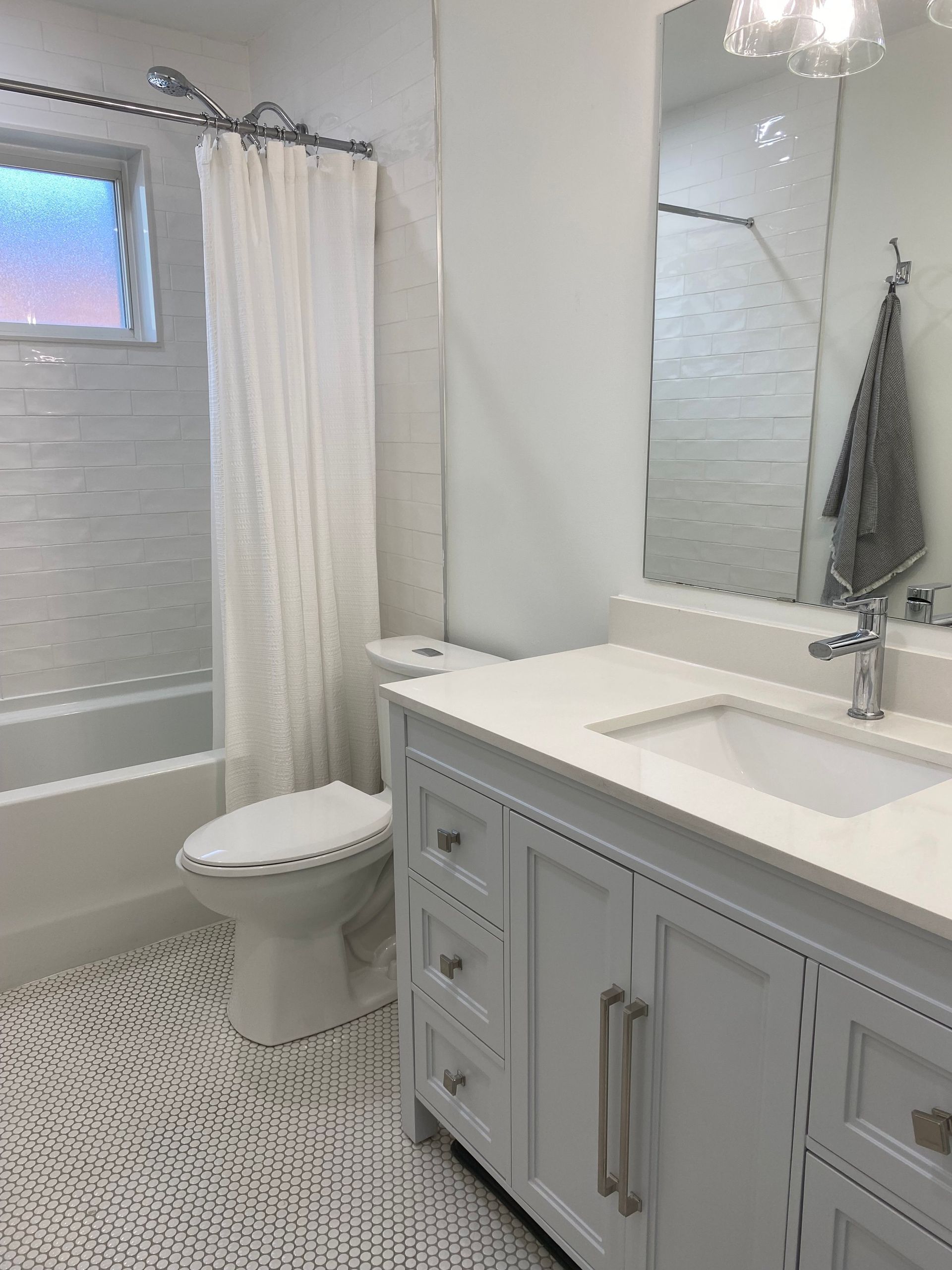 A bathroom with a toilet , sink , mirror and shower curtain.