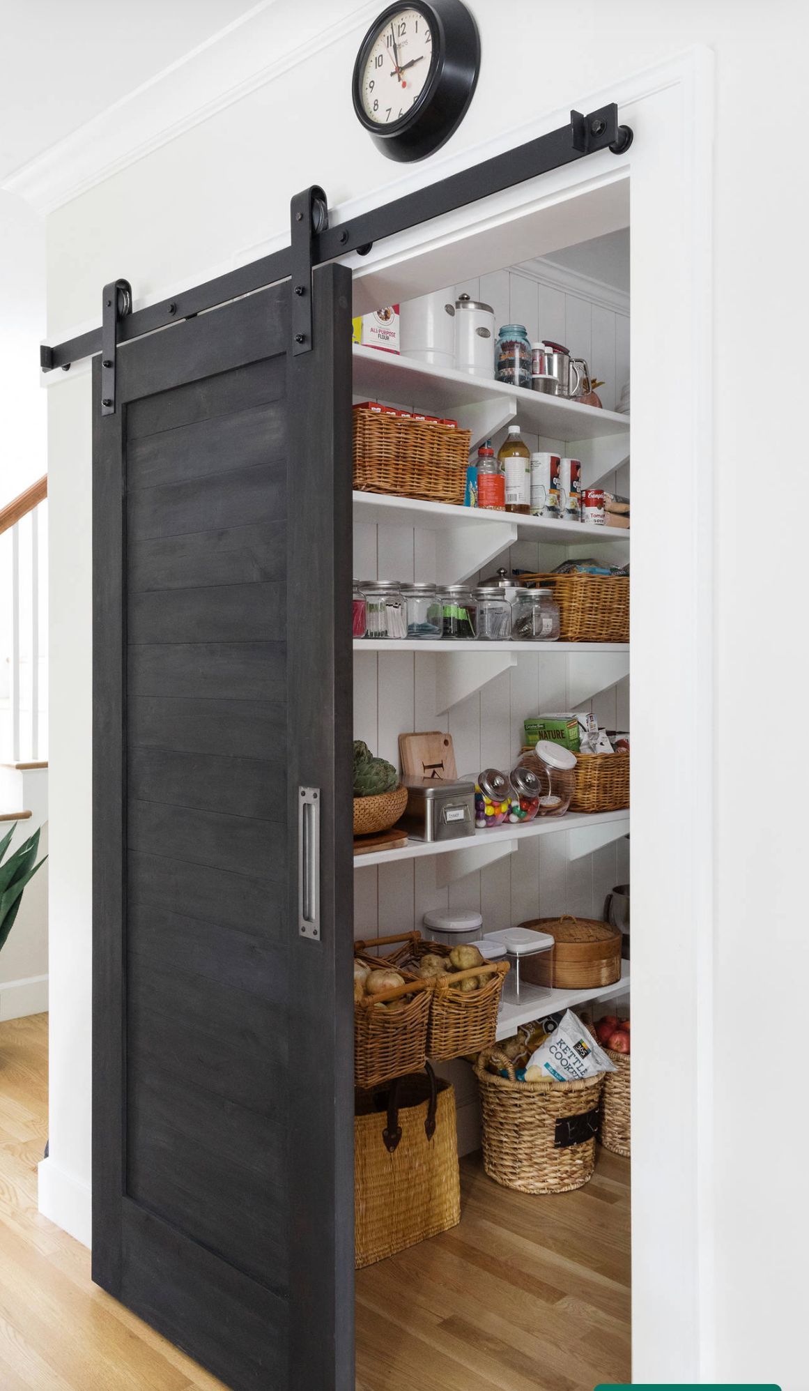 A pantry with a sliding barn door and a clock on the wall.