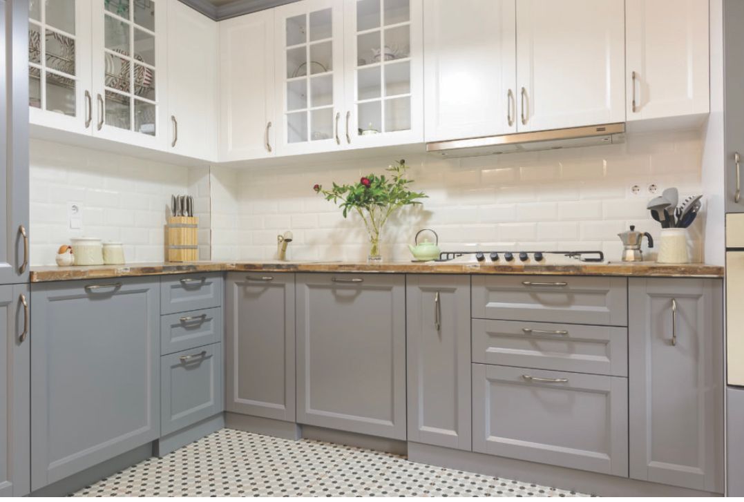 A kitchen with gray and white cabinets and a tiled floor.