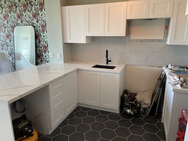 A kitchen with white cabinets and a black sink