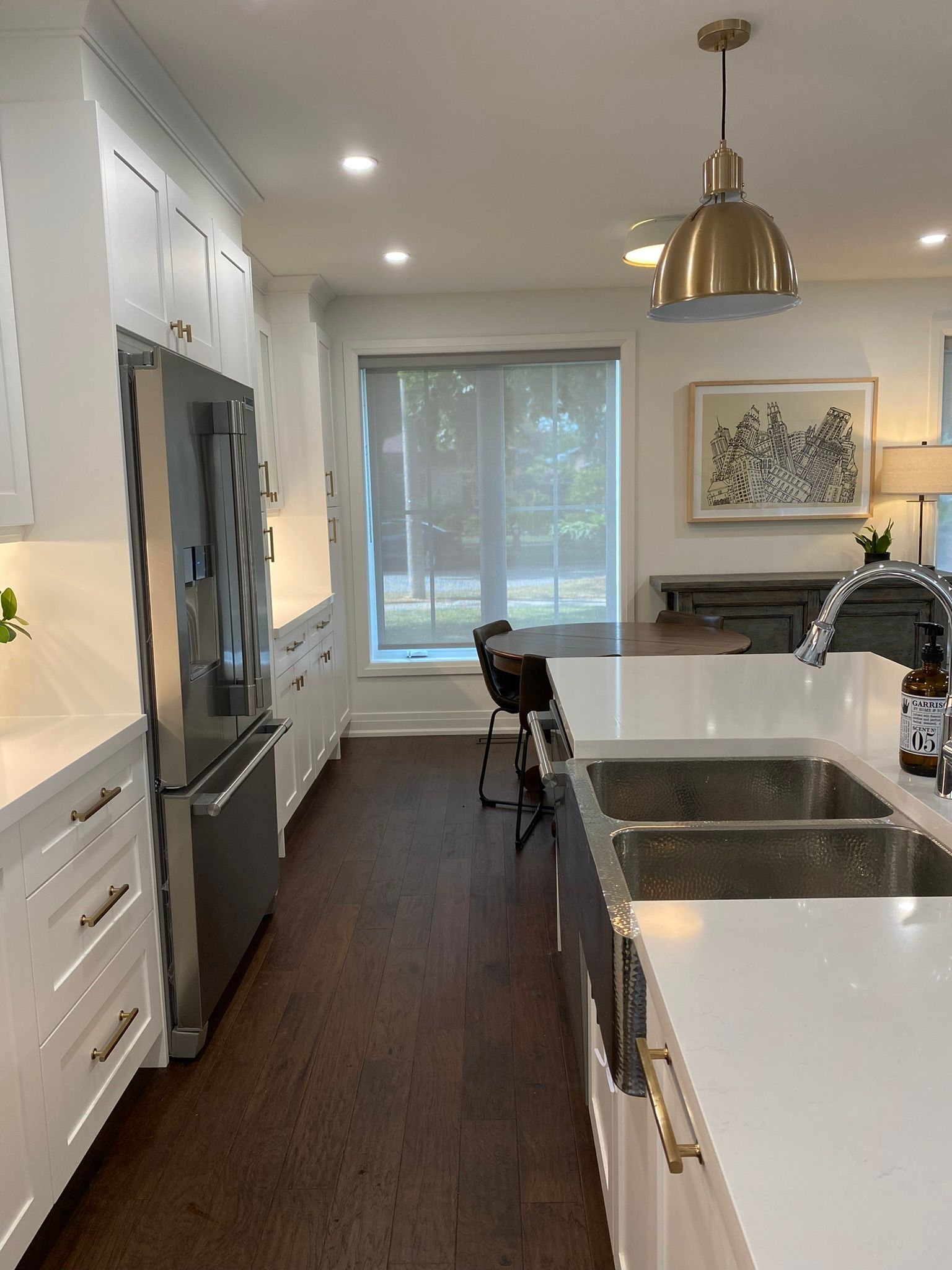 Modern kitchen with white cabinets, stainless steel refrigerator, and large island with sink.