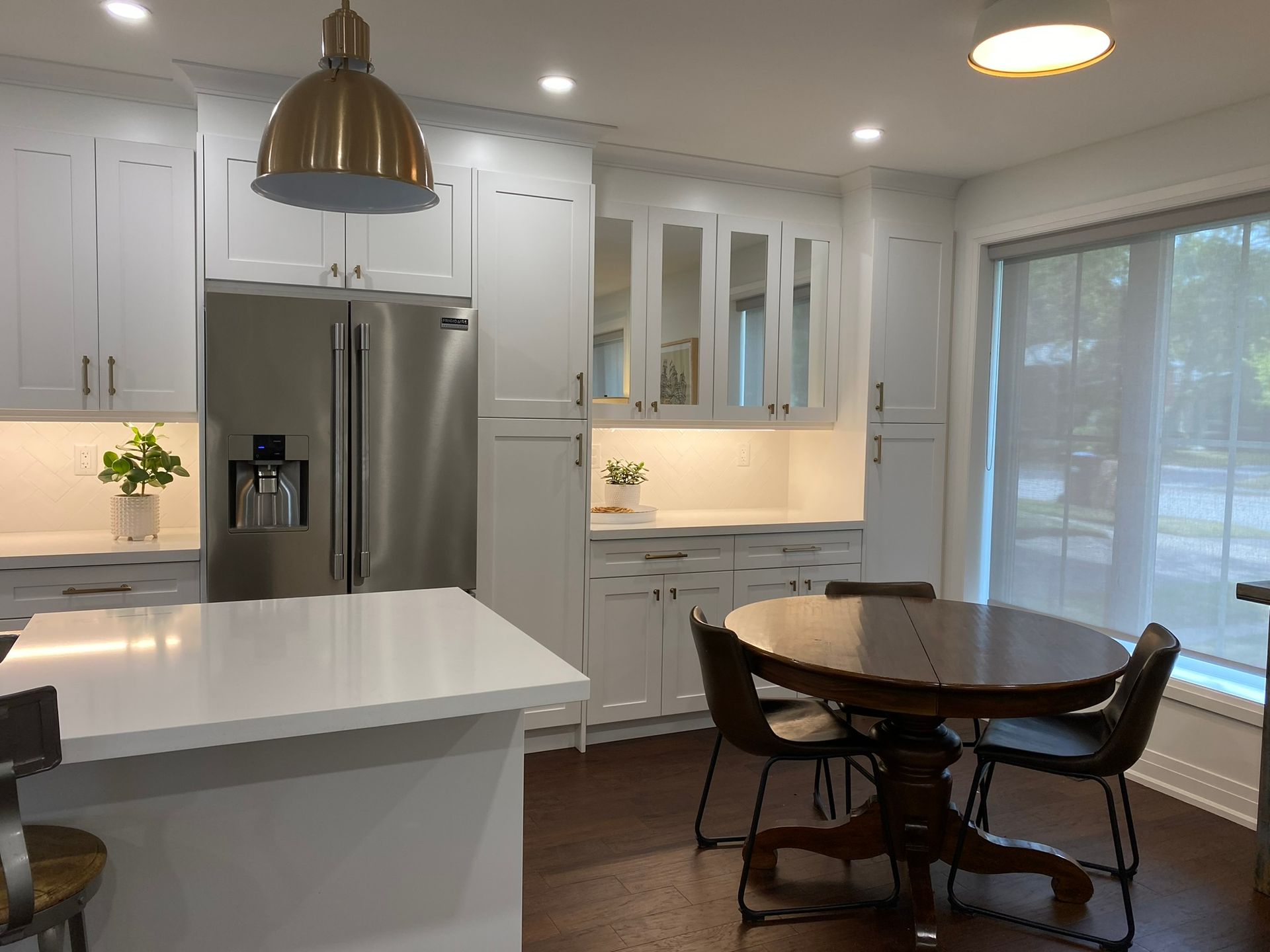 White kitchen with stainless steel appliances, white cabinets, and a wooden table with chairs.