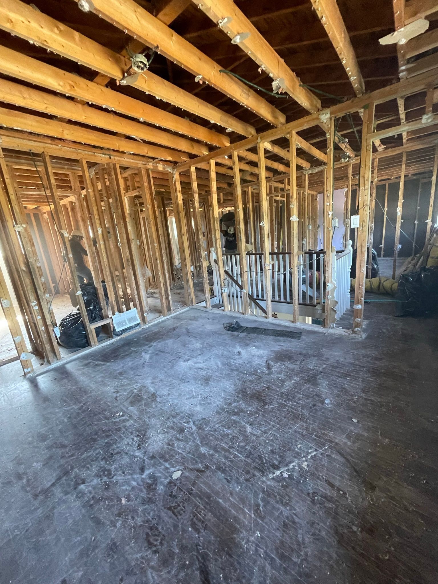 A room with wooden beams and a concrete floor in a house under construction.