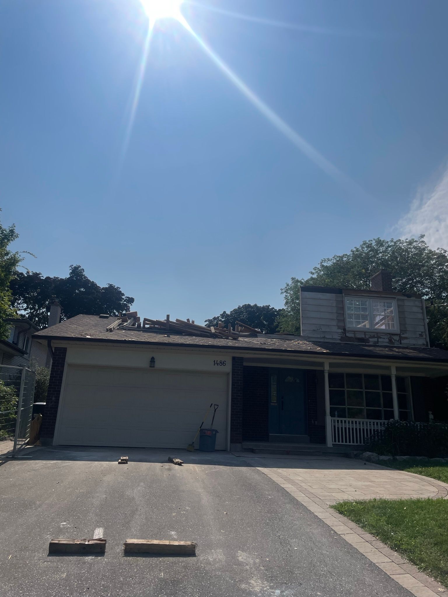 The sun is shining brightly on a house with a white garage door.
