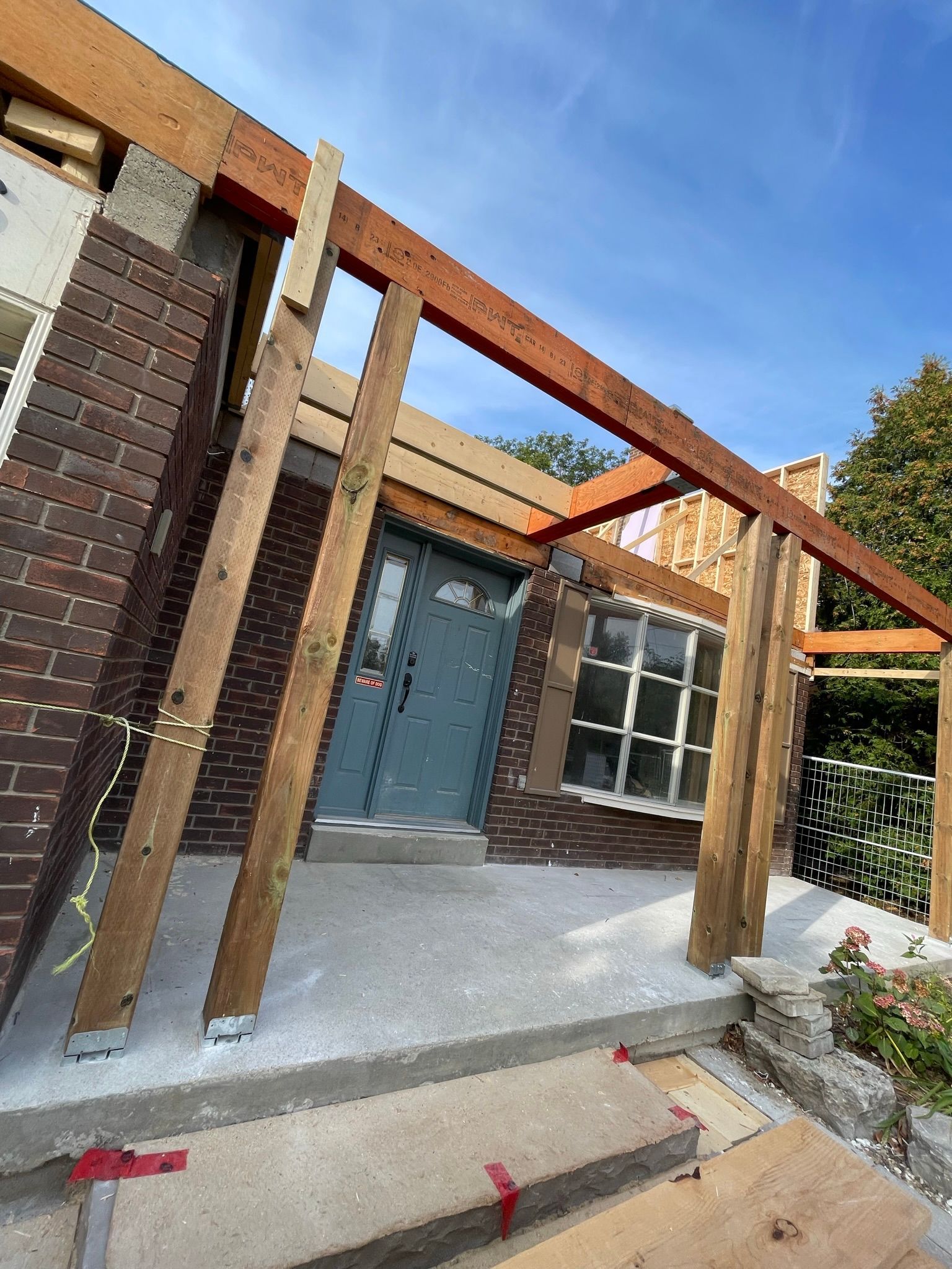 A brick house is being remodeled with wooden beams.