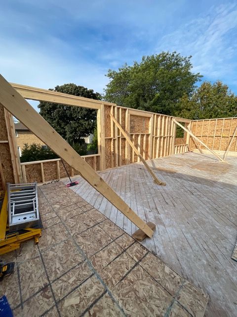 Wood frame of a building under construction, walls and floor in place, with a blue sky background.
