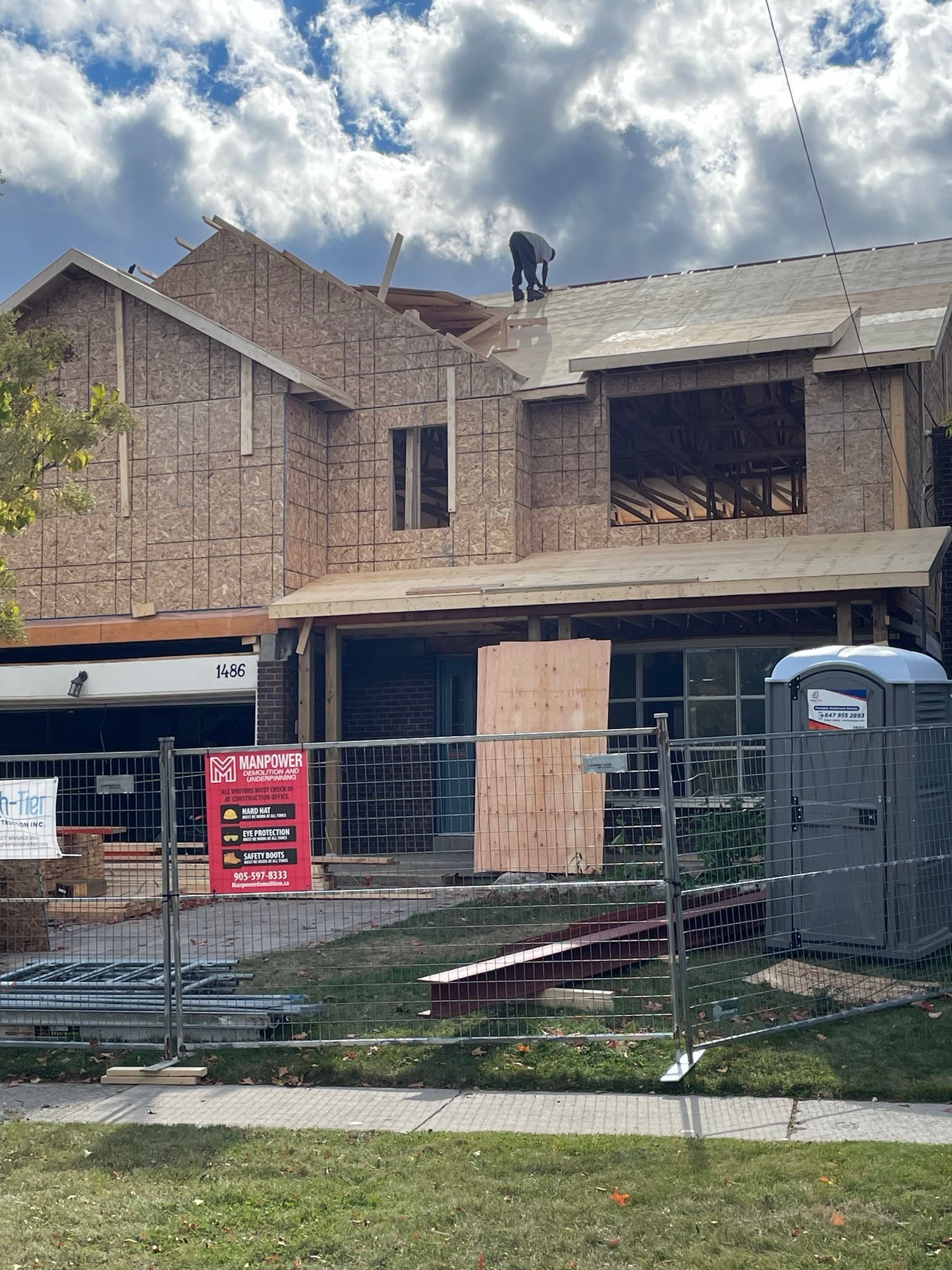 A house is being built with a portable toilet in front of it.