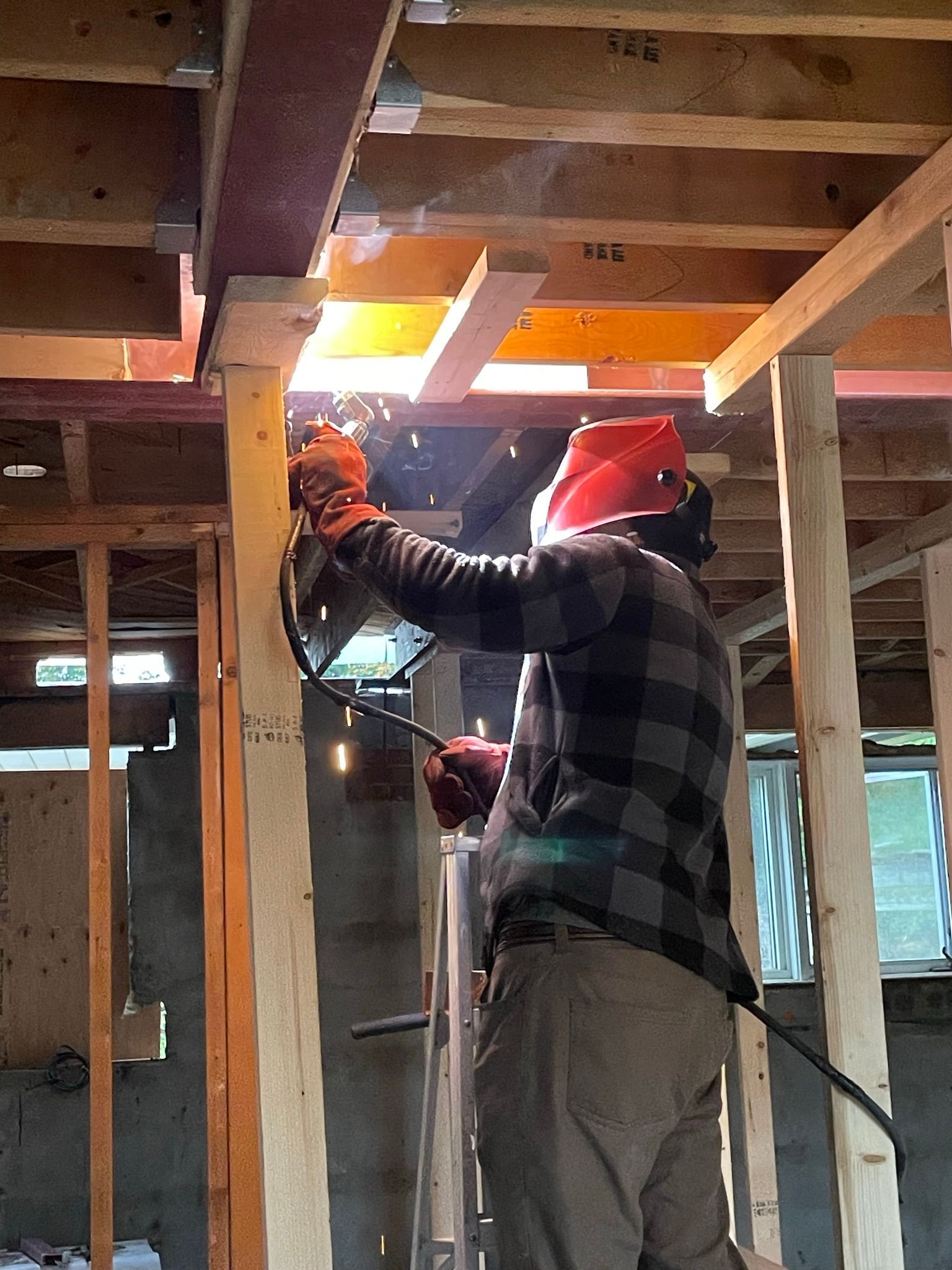A man is welding a piece of wood in a building under construction.