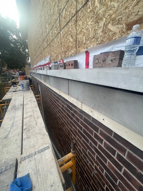 Brick building under construction, with scaffolding and water bottle on ledge.