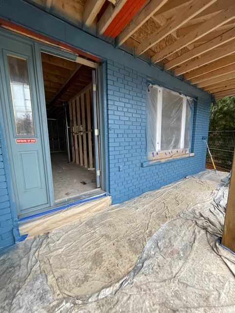 Blue painted brick exterior of a building with doorway, window, and protective sheeting.