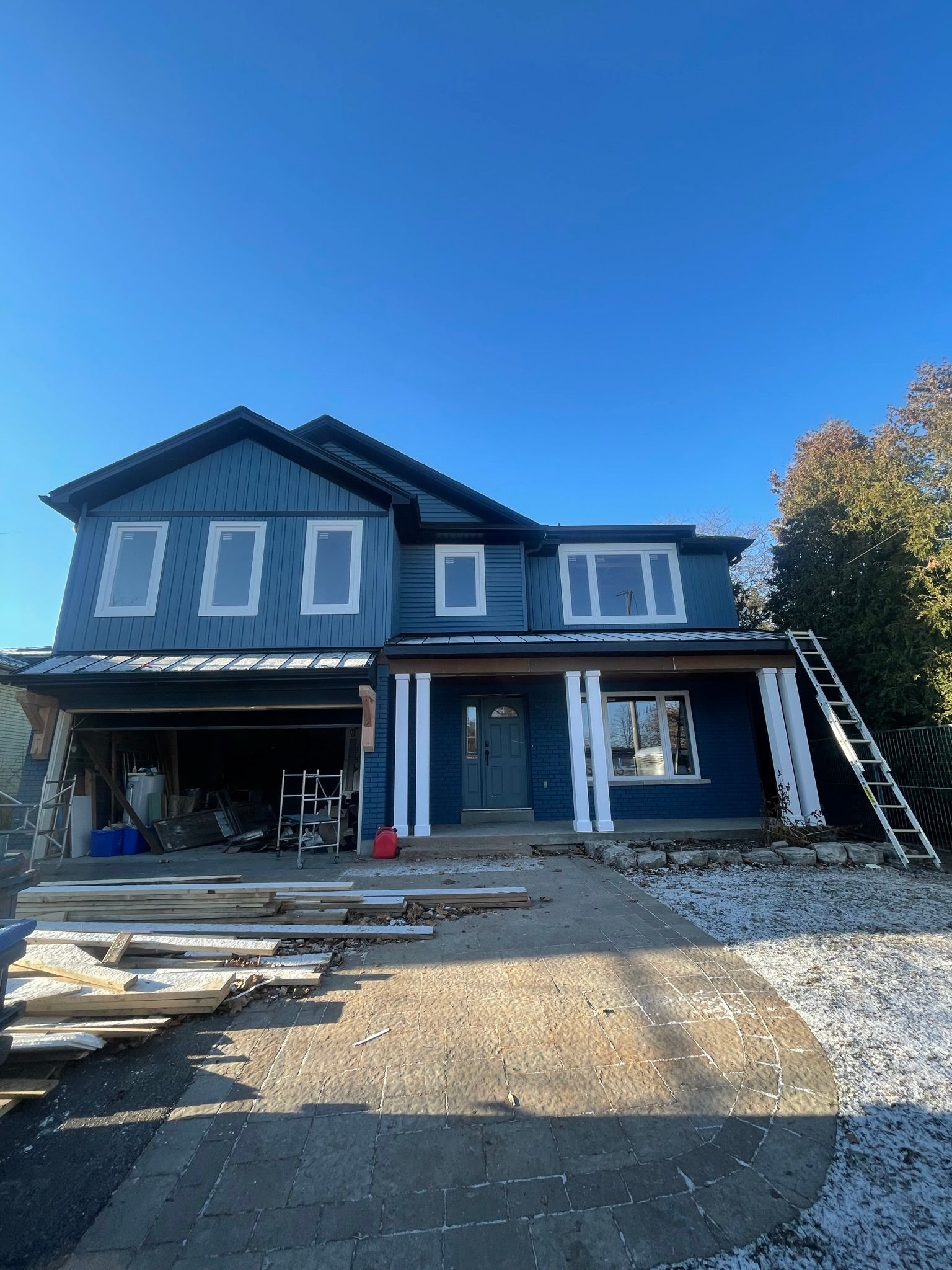 A blue house with white trim is being painted.