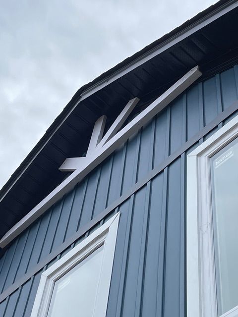Blue siding with white trim, roof peak with decorative wooden brackets.