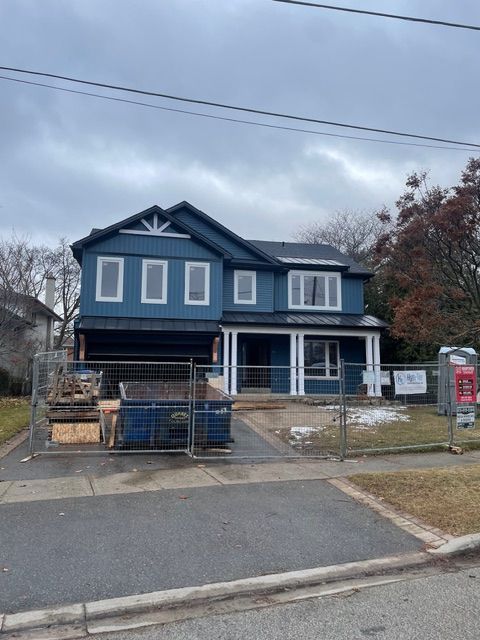 Two-story blue house under construction, with a front porch, windows, and a dumpster in the front yard.