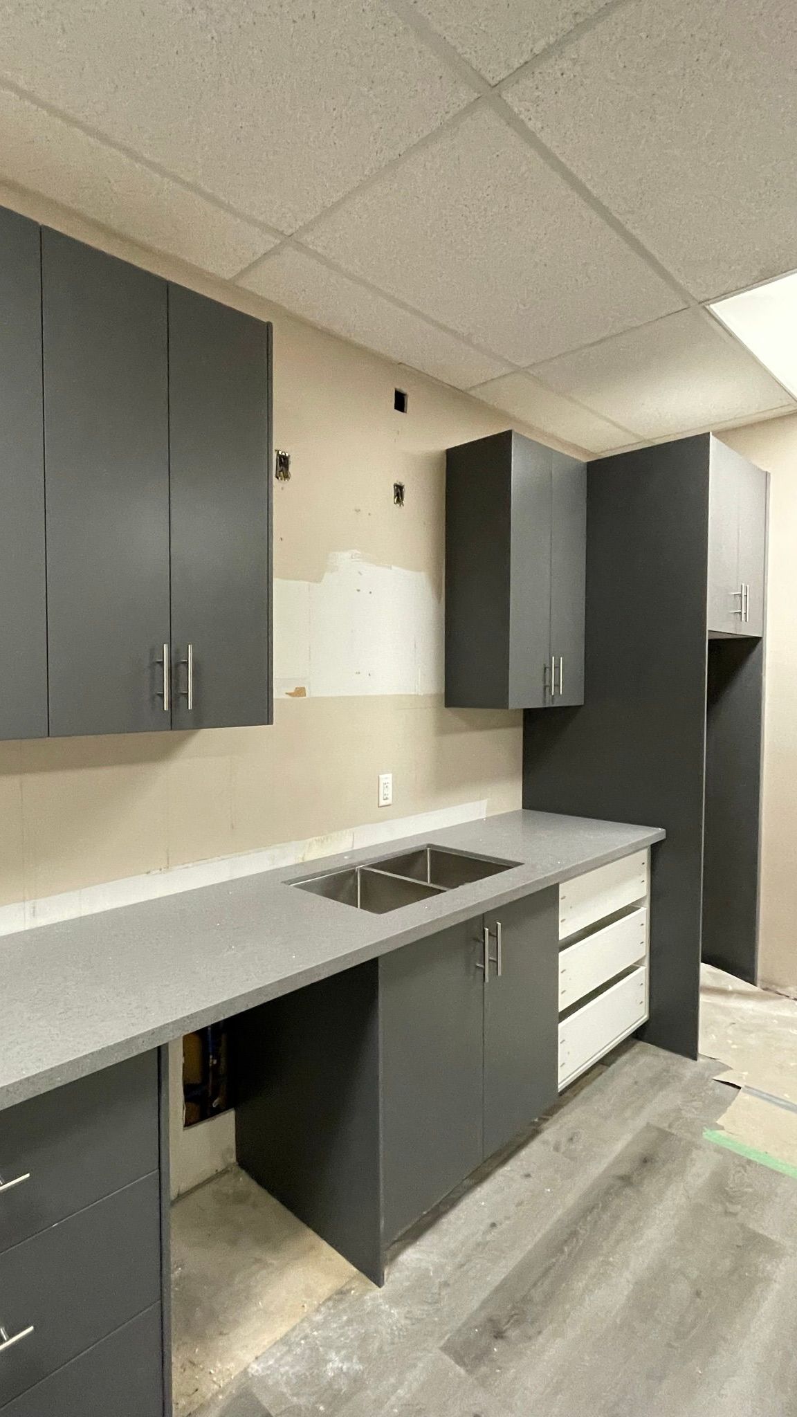 A kitchen with a sink , cabinets , and counter tops.