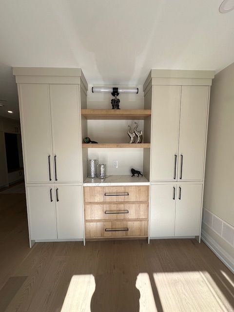 A room with white cabinets and wooden drawers and shelves.