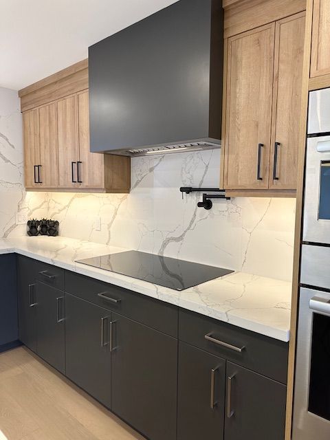 A kitchen with a stove top oven , stainless steel appliances , and wooden cabinets.
