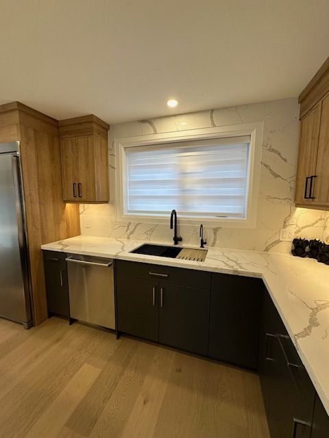 A kitchen with a sink , dishwasher , refrigerator and a window.