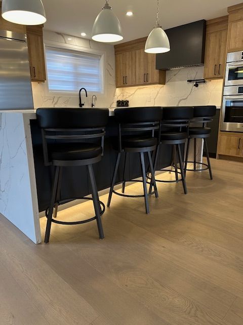 A kitchen with black stools and a white counter top