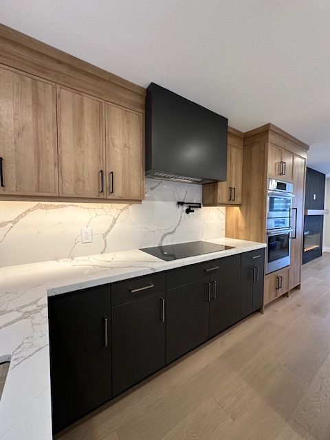 A kitchen with wooden cabinets , black cabinets , a stove top oven , and a flat screen tv.
