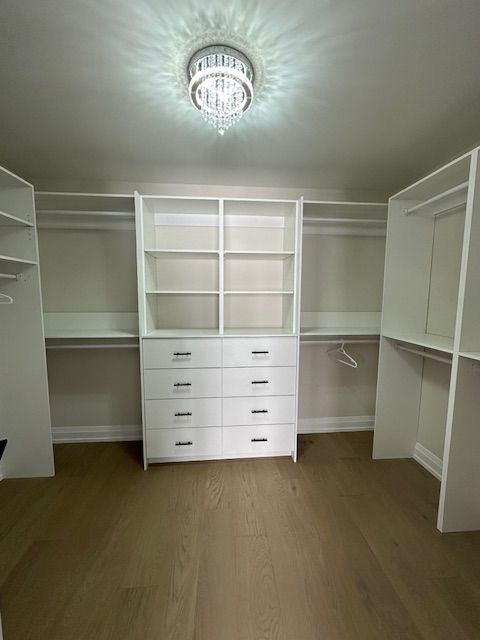 A walk in closet with lots of shelves and drawers.