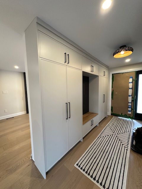 A hallway with white cabinets and a rug on the floor.