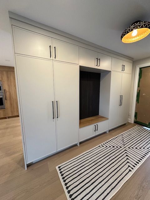 A hallway with white cabinets and a black and white rug.
