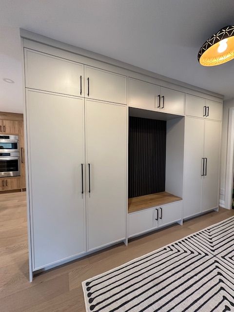 A kitchen with white cabinets and a black and white rug.