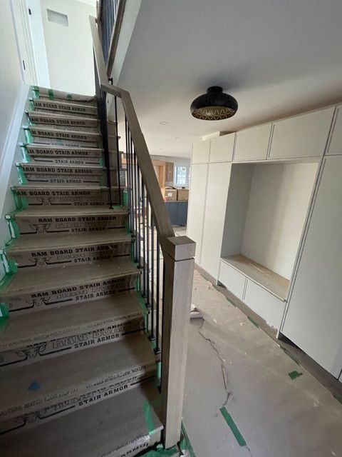 Staircase with wooden steps and railing, leading up. Built-in white storage and a light fixture on the ceiling.