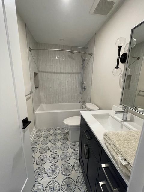 Bathroom with blue and white patterned tile floor, white walls, and dark blue vanity.